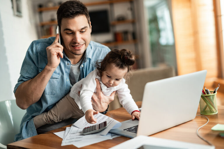 Daddy juggling holding an infant while talking on the phone