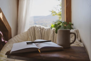 Notebook and coffee mug in front of a window