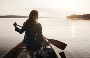 Paddling along the calm waters. Rearview shot of a young woman enjoying a canoe ride at the lake