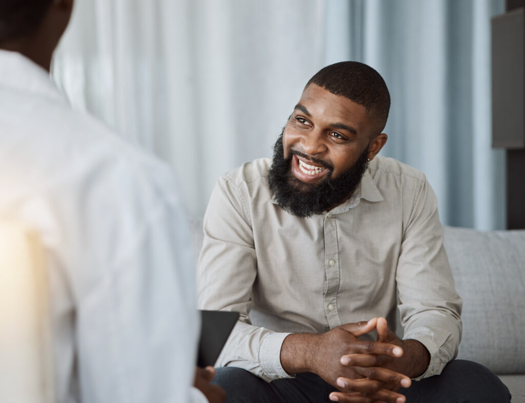 Happy black man, therapist and consultation in meeting for healthcare, mental health or therapy at the hospital. African male person talking to consultant in physiology, counseling or medical help.