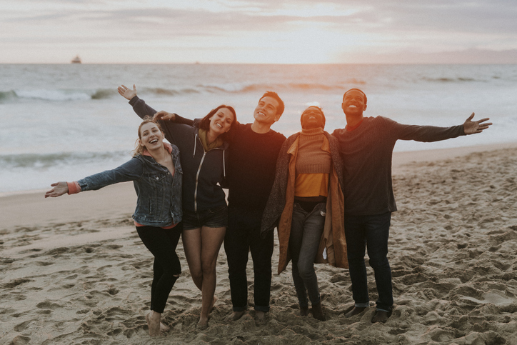 Happy friends enjoying the beach at sunset