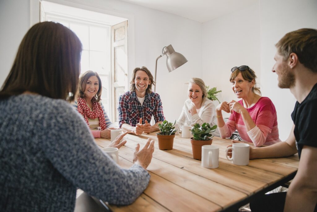 Group of employees at a small coffee shop sitting around a table having a meeting.