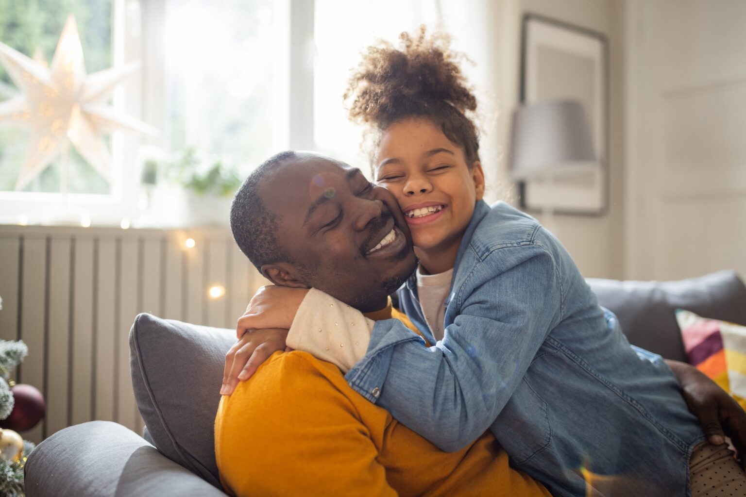 Father and daughter sitting on sofa and spending quality time together for Christmas.